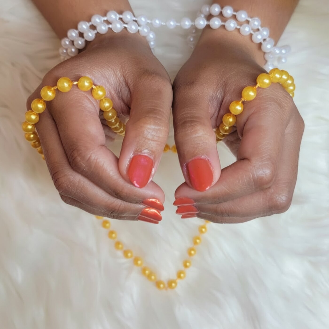 Coral shimmer manicure framed by yellow and white pearls