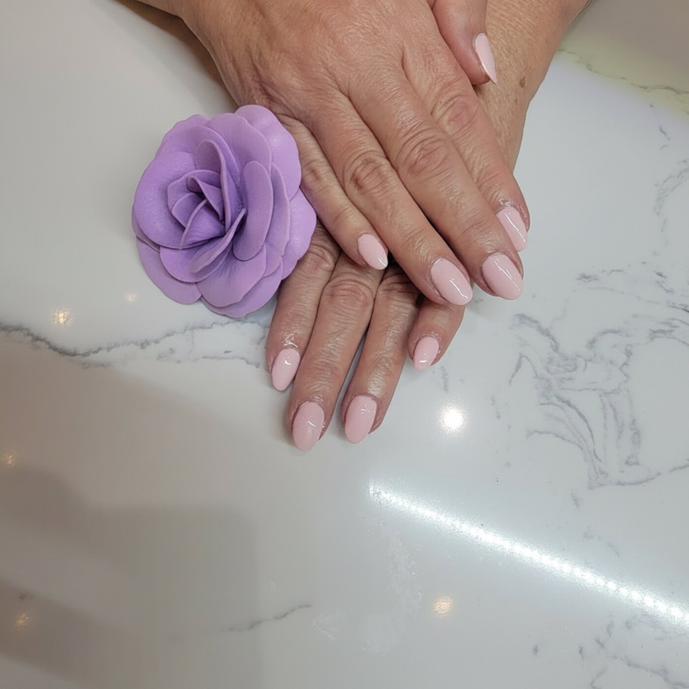 Classic pink almond gel manicure on marble countertop